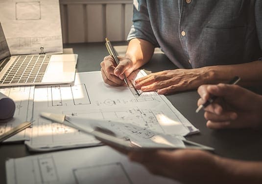 Architectural team reviewing technical drawings for building regulations and tender preparation.