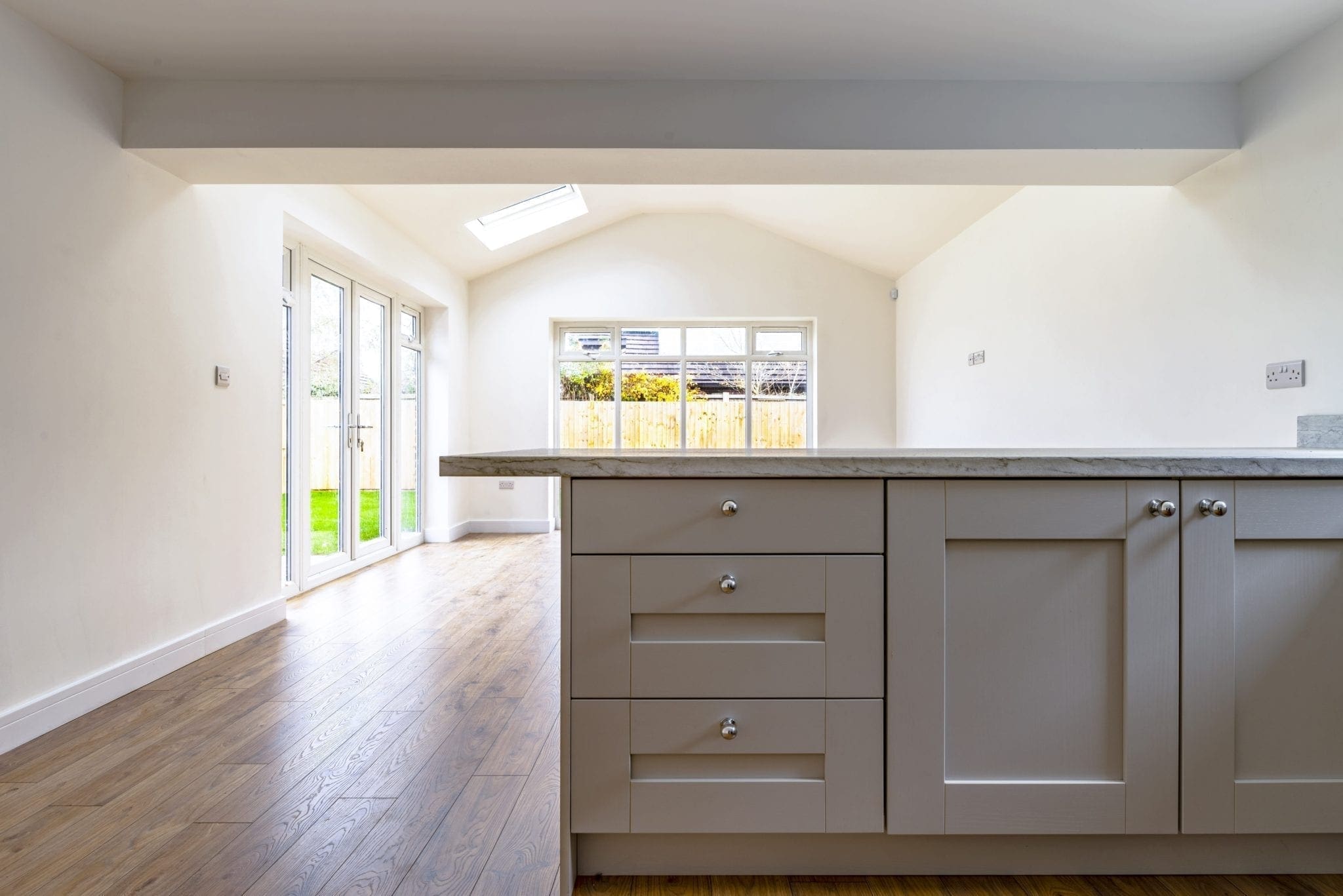 Open-plan kitchen and dining space with shaker cabinetry, timber flooring, a rooflight and French doors to the garden.