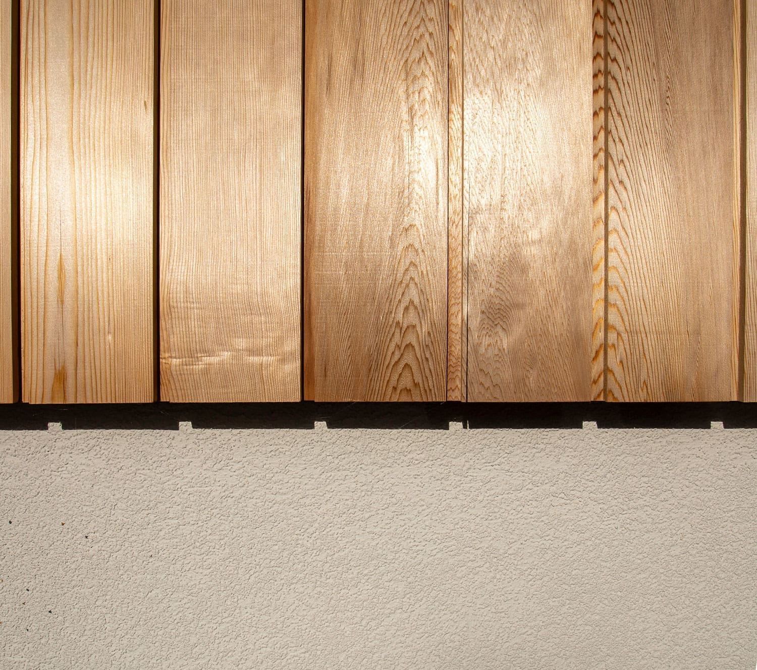 Close-up of vertical timber cladding above the rendered ground-floor wall.