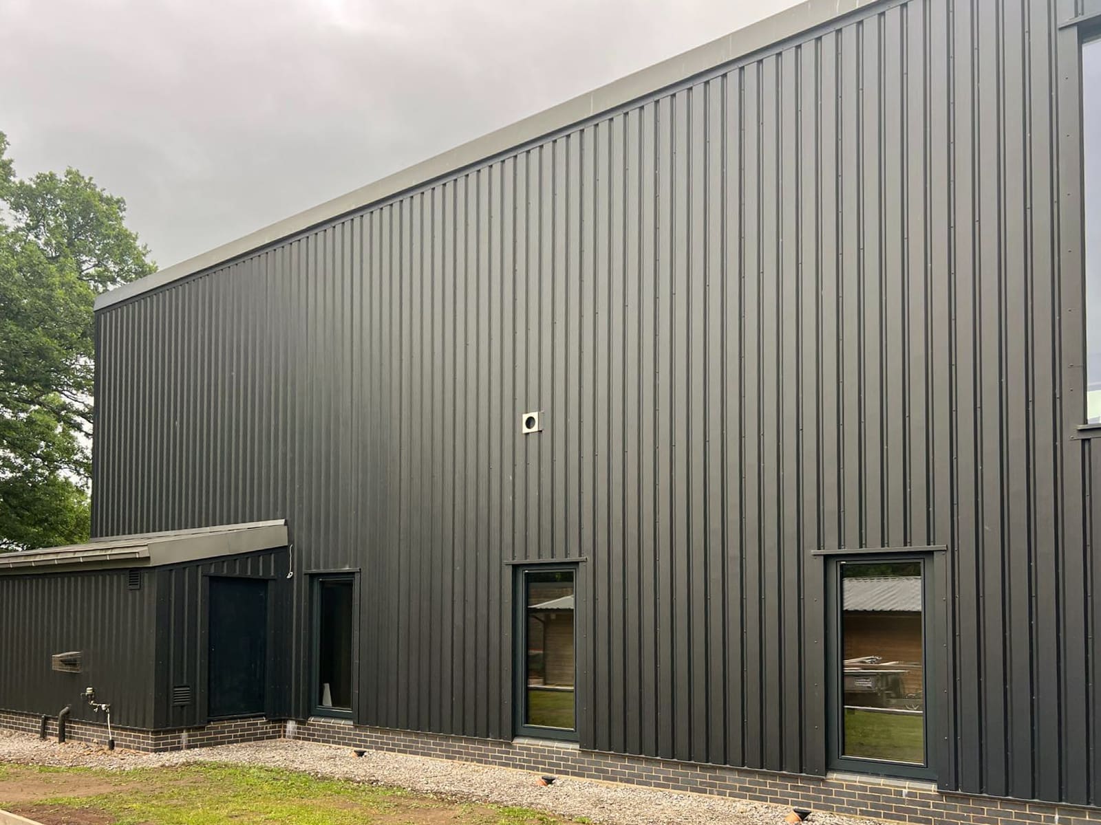Close view of the black vertical metal cladding and narrow windows on the side elevation.