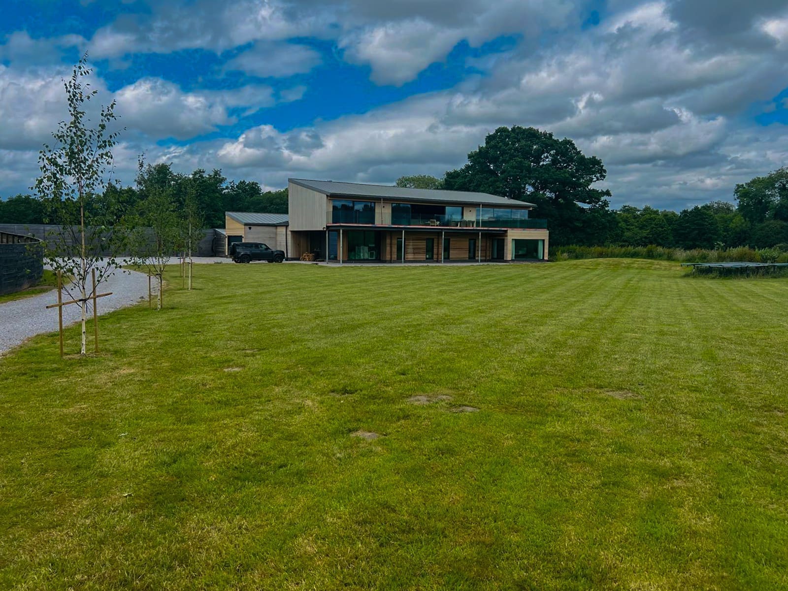 Wide garden view of The Mousetrap, a contemporary timber-clad home set within a large lawn.