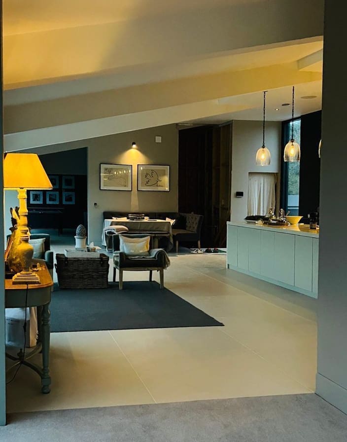 Open-plan lounge and kitchen illuminated by warm lamps in the evening.