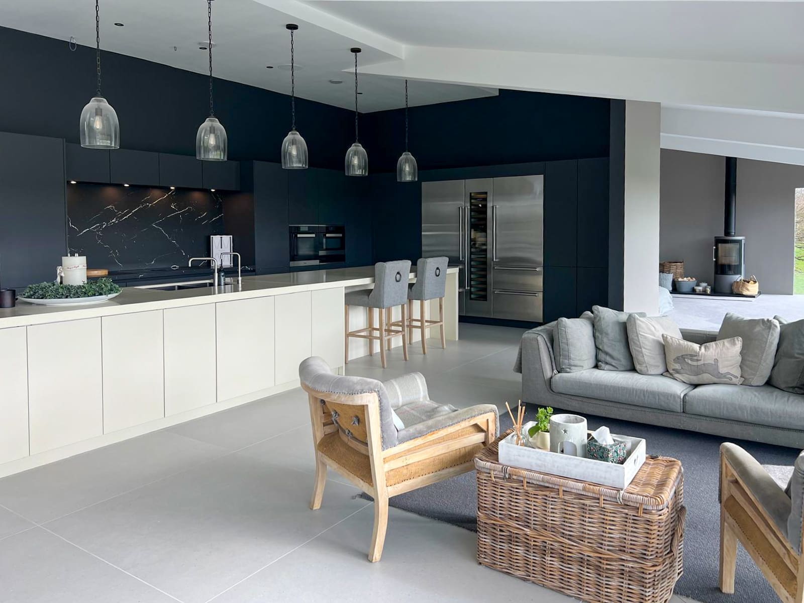 Open-plan kitchen and lounge with a large island, dark cabinetry and wood-burning stove.