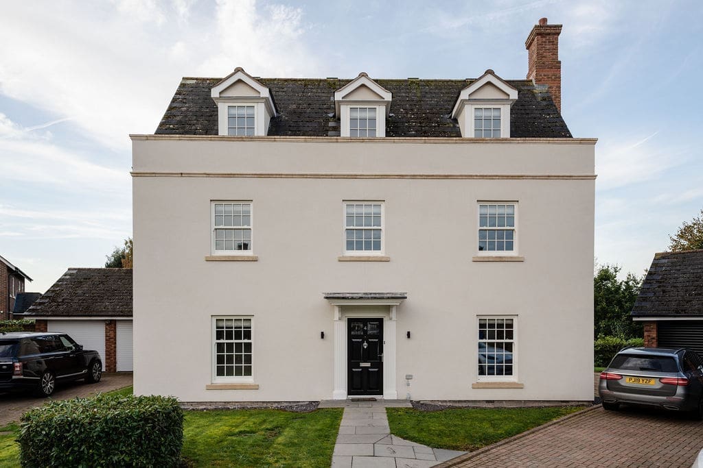 Front elevation of Oakdale with a rendered façade, dormer windows and a central black entrance door.